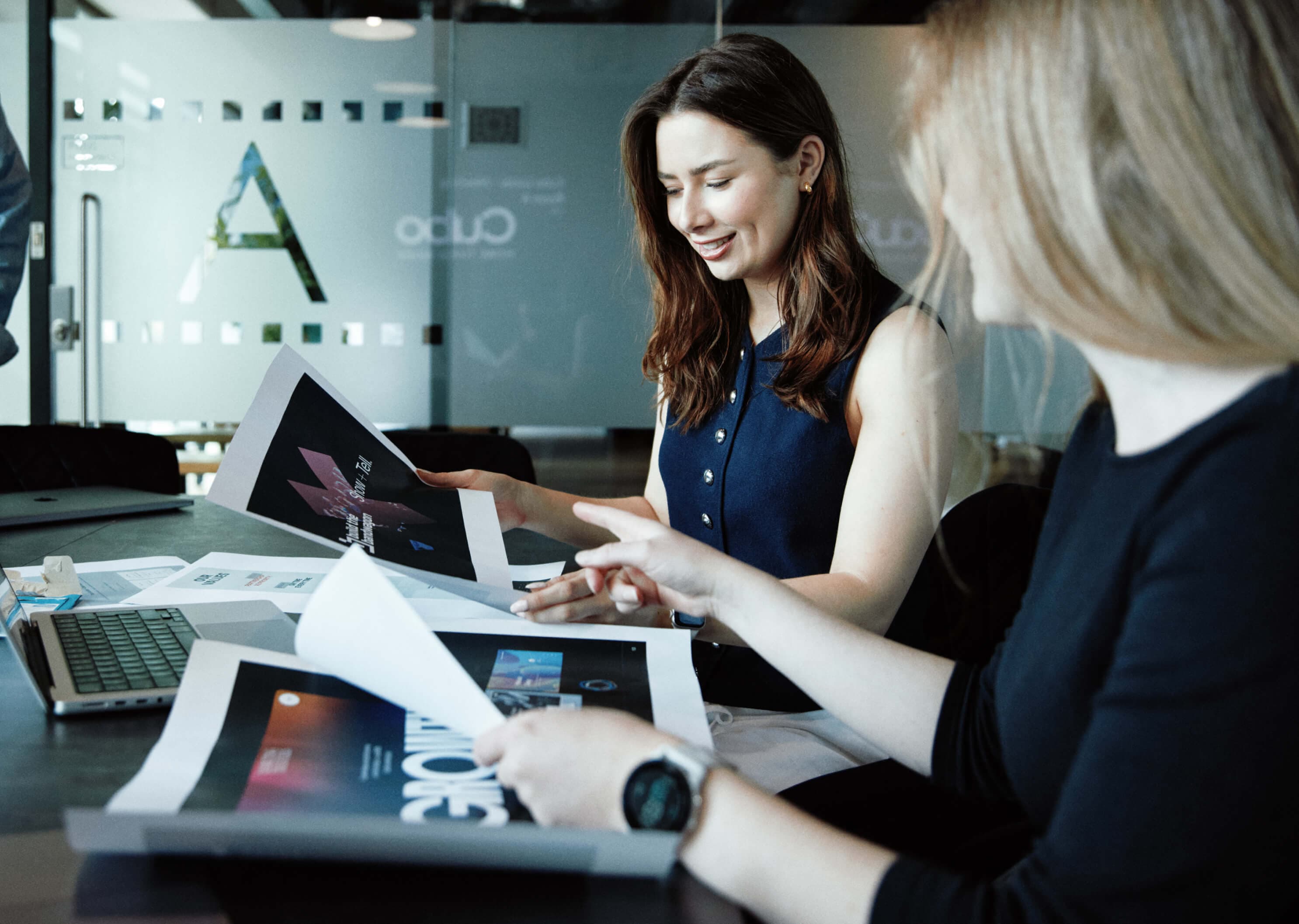 Designers examining multiple branding concepts, thumbing through printed boards filled with colour palettes, typography, and mockups.